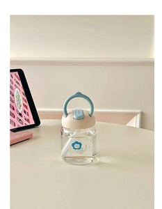 Close-up of a cute cat patterned glass cup with a straw and blue carry handle