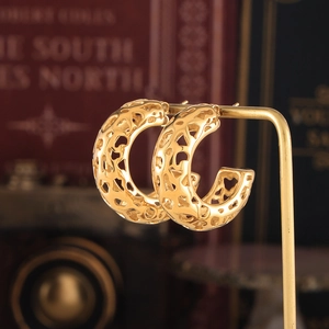 Golden geometric hollow C-shaped earrings in polished titanium steel on a display stand