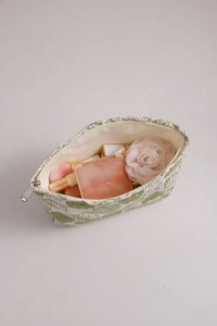 Detail of white cotton linen cosmetic bag with green leaf embroidery and metal zipper