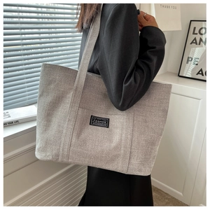 Detailed view of gray large capacity canvas tote bag worn by a model in a modern room