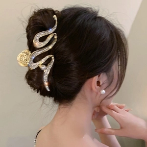 Detail of elegant gold wave hair claw clip with rhinestones and pearl on model's hair