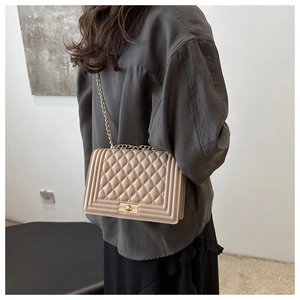 Detail of beige quilted shoulder bag with golden chain strap and metallic square lock