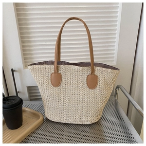 Detailed close-up of straw beach tote bag with brown faux leather straps and metal stand
