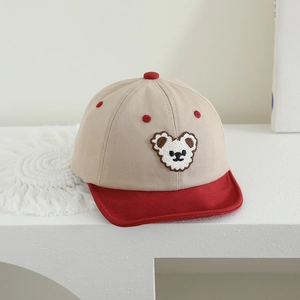 Close-up of baby baseball cap featuring beige and red panels with cartoon bear embroidery