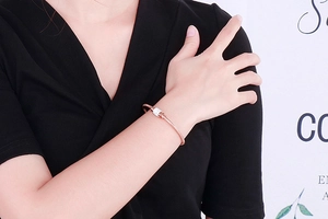 Gros plan d'un bracelet maille serpent or rose avec un charm cylindre pavé de cristaux