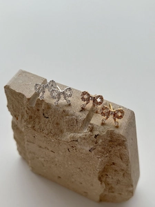 Macro detail of luxury bow earrings in gold, silver and rose gold with pavé crystals
