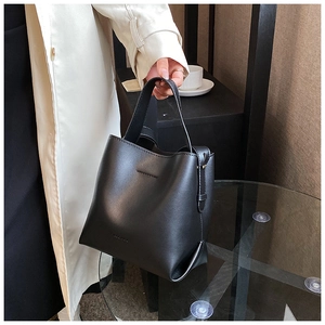 Detail of a vintage black leather bucket bag held by a model in a stylish setting