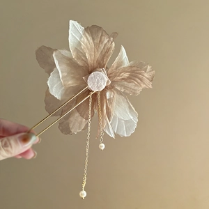 Detailed view of floral hair pin with chiffon petals, gold tassels and white pearls