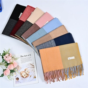 Flat lay of cashmere-feel scarves with colorful patchwork designs and tassels