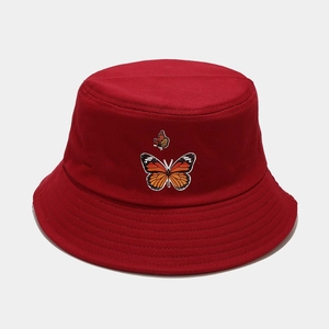 Vue détaillée des motifs de papillons brodés sur un chapeau bob en coton rouge foncé