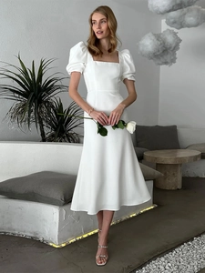 Detail of square neckline and puff sleeves on a minimalist white A-line dress