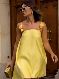 Detail of elegant yellow satin slip dress featuring 3D floral decoration on the shoulder strap