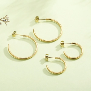 Detailed close-up of golden spiral twisted C-shape hoop earrings in two sizes