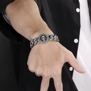 Macro view of men's stainless steel skull bracelet with Greek key pattern on wrist