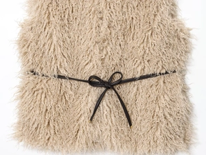 Detailed macro view of curly beige faux fur texture with a slim black bow waistband