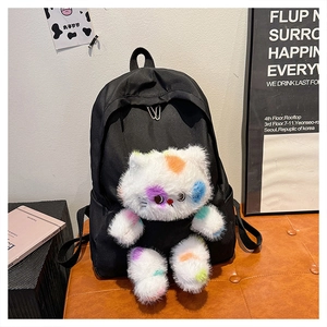 Dettaglio del ciondolo a gatto in peluche con macchie colorate su zainetto nero