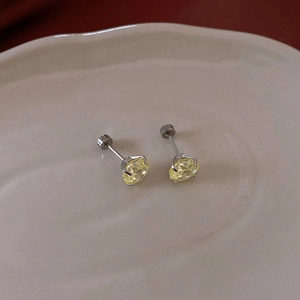 Detailed macro view of classic round cut yellow zircon stud earrings in silver prong setting