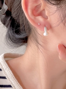 Close-up of elegant silver pearl drop earrings worn by a model in a minimalist style
