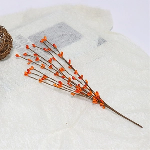 Close-up of artificial orange berries branches on a white knitted fabric background