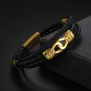 Détail du bracelet multicouche en cuir noir avec boucle magnétique gravée dorée sur boîte
