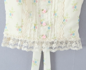 Détail de la bordure en dentelle florale et des boutons de rose sur haut mousseline