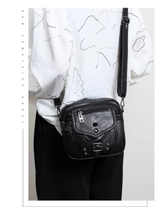 Détails de la texture en cuir lavé et des rivets métalliques sur le sac à bandoulière noir