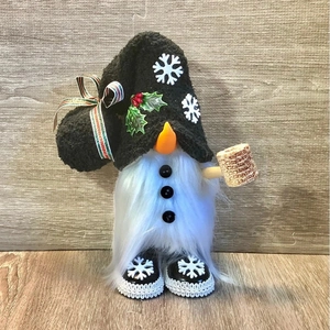 Christmas gnome doll with black plush hat and snowflake pattern on wooden background