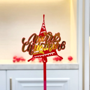 Detail of red acrylic Merry Christmas cake topper with golden text for party decor