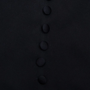 Detailed macro view of black fabric covered buttons and textured fabric on suit dress