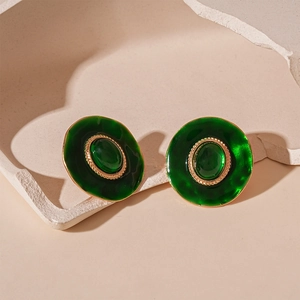 Gros plan détaillé de boucles d'oreilles vintage en émail vert et textures dorées