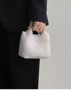 Detail view of a white hand-woven mini bucket bag with a soft textured finish