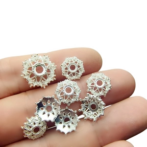 Macro detail of silver hollow patterned metal flower bead caps for DIY jewelry making