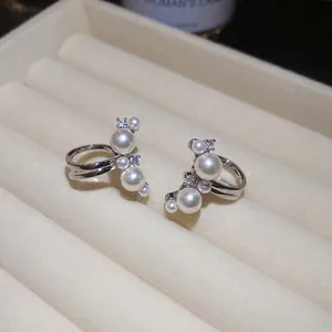 Elegant vintage zircon and pearl ear clips in silver setting displayed on a jewelry box