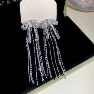 Detailed close-up of zircon bow earrings with long sparkling tassels on a black background