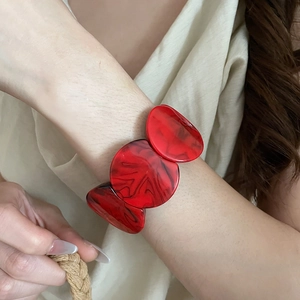 Close-up of a large red marble acrylic bangle with unique black swirling textures