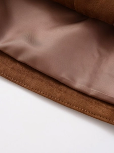 Macro shot of double-stitched caramel suede jacket hem with smooth satin lining detail