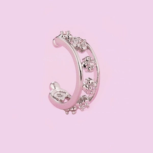 Detail of silver double-layered ear cuff with four zircon floral accents on purple backdrop