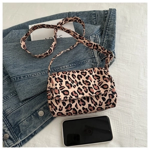 Flat lay of a trendy leopard print crossbody bag with wide strap and fashion props