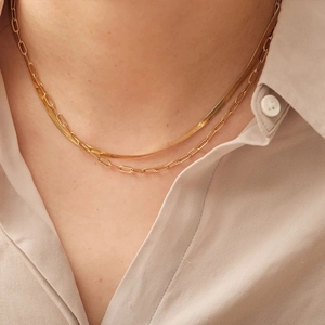 Double-layered gold necklace with snake chain and paperclip link design on a model