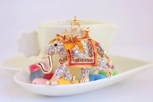 Close-up of running elephant keychain with colorful rhinestones on a white heart dish