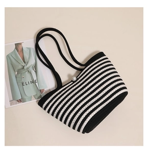 Top-down view of striped woven shoulder bag featuring black straps and a pearl closure detail