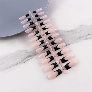 Detail of long ballerina press-on nails with black French tips on white marble surface
