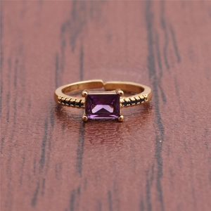Detailed top view of purple rectangular crystal ring with gold band on wood surface