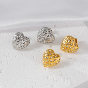 Detail of silver and gold heart stud earrings with woven texture and sparkling crystals