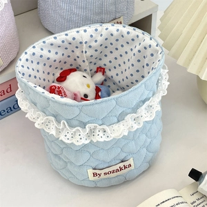 Quilted fabric storage basket with lace trim and polka dot lining in home setting