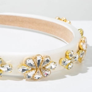 Gros plan sur un serre-tête en satin blanc avec fleurs en cristal doré et strass
