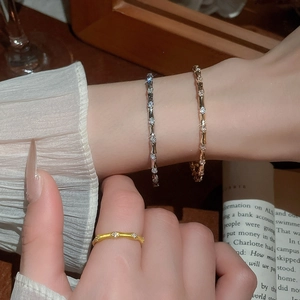 Detailed view of zircon-studded bamboo-style gold and silver bracelets on a wrist