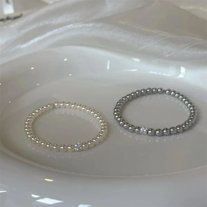 Minimalist pearl bracelet with square zircon in white and grey colors on silk background