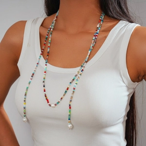 Detail of colorful beaded long necklace with white pearl accents worn by a female model