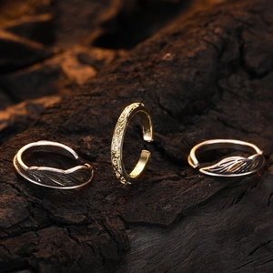 Three-layer detachable feather rings in gold and silver finish on wood background
